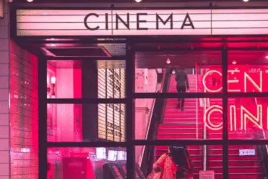 Brightly lit entrance of Central Cinema with neon red lighting and people walking in.