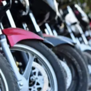Row of parked motorcycles aligned on a street in daylight, focusing on the front wheels.