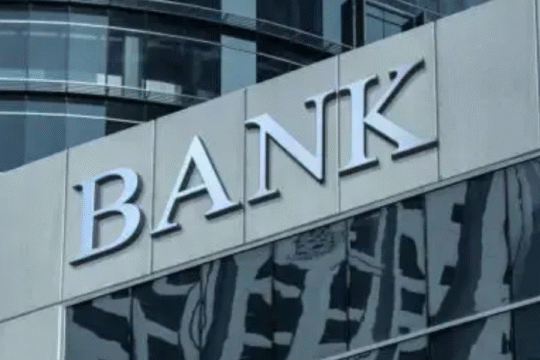 Modern glass-fronted commercial bank building with the word "BANK" prominently displayed on the exterior.