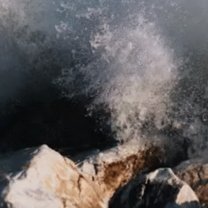 Powerful ocean waves crashing dramatically against rugged coastal rocks, creating a misty spray.