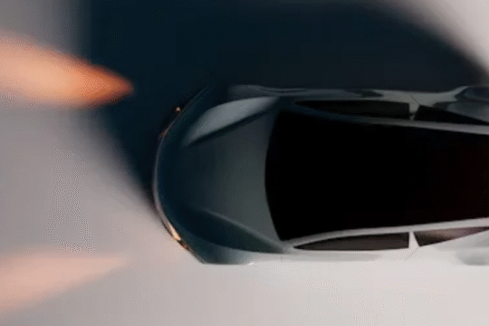 Top view of a modern white car with illuminated headlights and taillights on a dimly lit surface