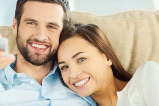 A confident young woman wearing sunglasses, posing outdoors with modern architecture in the background under natural daylight.