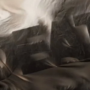 A distorted cloth-like material with dark shadows partially conceals the word "DEATH" underneath, creating an abstract and eerie visual effect.