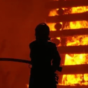 Firefighters battling intense flames during a massive blaze at an industrial site at night.