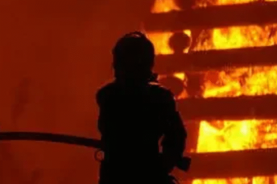 Firefighters battling intense flames during a massive blaze at an industrial site at night.