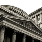 Historic stone bank building with classical architecture and Corinthian columns, viewed from a low angle.