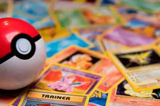 A Poke Ball rests on a pile of scattered Pokémon trading cards.