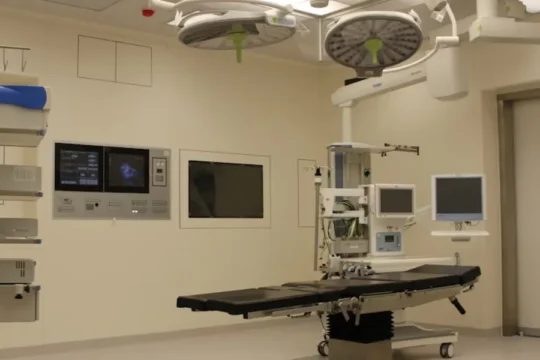 A modern, well-equipped operating room with a surgical table and medical machinery.
