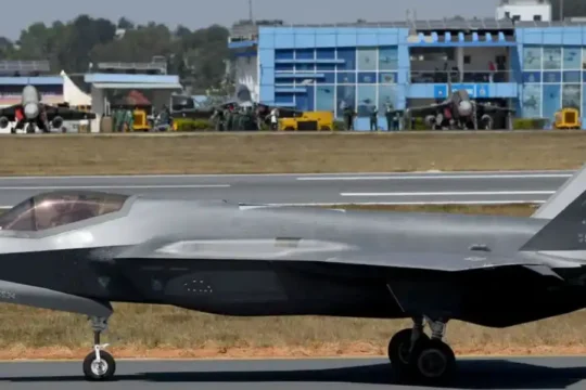 An F-35 fighter jet, marked with "AK" on its tail