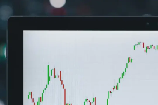 A close-up of a laptop screen displaying a stock market candlestick chart.