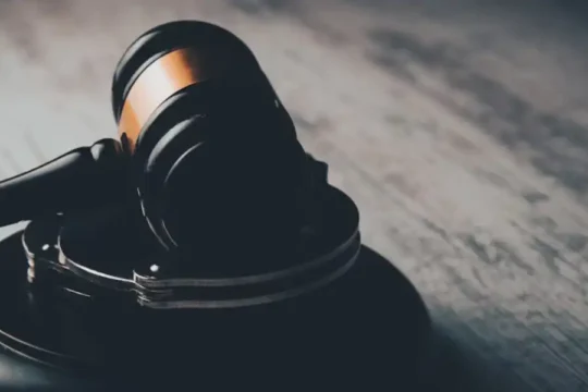 A dark, moody close-up of a wooden gavel on a table.