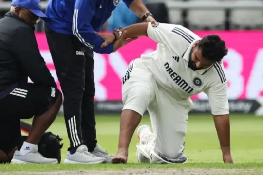 Cricketer on knees, receiving assistance from two support staff.