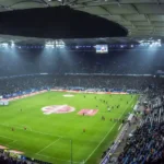 High angle view of a large, illuminated football stadium at night.