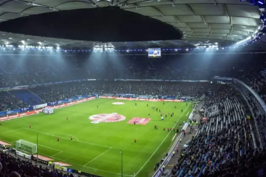 High angle view of a large, illuminated football stadium at night.
