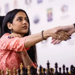 Indian female chess player extends hand for handshake during a match.