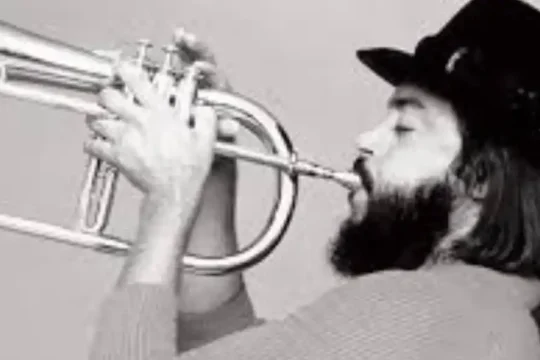 Black and white photo of a bearded man playing a flugelhorn.
