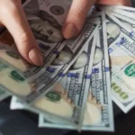 Hands fanning out a stack of one hundred dollar bills.