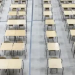 An overhead view of a large hall filled with rows of empty desks.