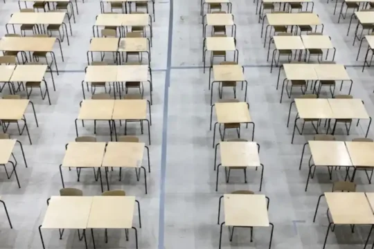 An overhead view of a large hall filled with rows of empty desks.