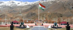 The Indian flag flies high at a war memorial in a mountainous region.