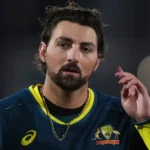 An Australian cricketer in uniform with a beard, looking thoughtfully.