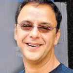 Actor vidhu vinod chopra smiling and wearing sunglasses.