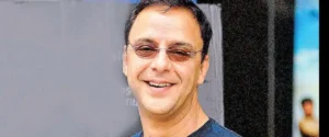 Actor vidhu vinod chopra smiling and wearing sunglasses.