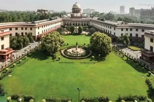 An aerial or wide shot of the Supreme Court of India building with its large green lawns.