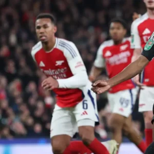 Football player in black and white striped jersey kicks the ball during a match