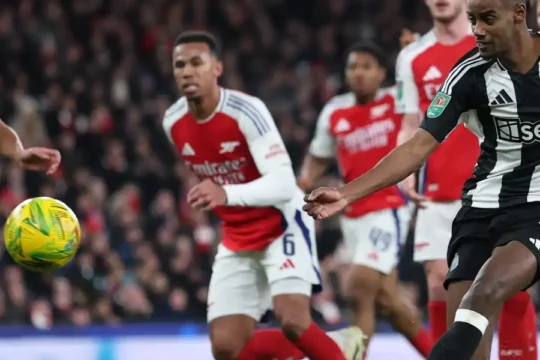 Football player in black and white striped jersey kicks the ball during a match