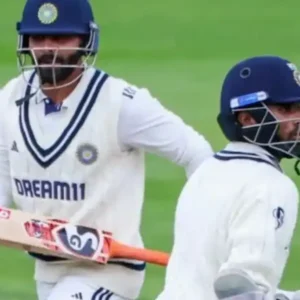 Two cricketers in white uniforms running between wickets on a green field