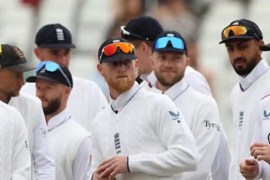The England cricket team in white uniform and caps, looking towards the left