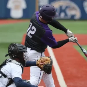 A baseball batter in a purple jersey hitting a ball, with a catcher and umpire behind him.