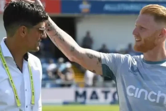 England cricketer Ben Stokes (right) with a hand on the head of Alastair Cook (left) on a cricket field.