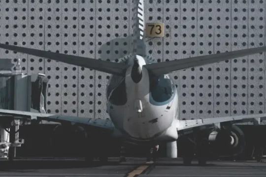 The rear view of a commercial airplane parked at an airport gate, with its tail number '73' visible.