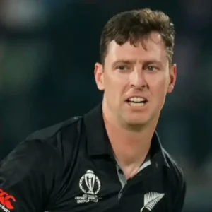 A male cricketer in a black New Zealand jersey, mid-action during a match.