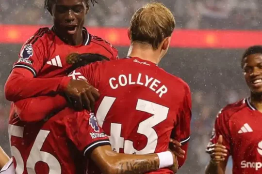 Soccer players in red jerseys celebrate enthusiastically on the field.