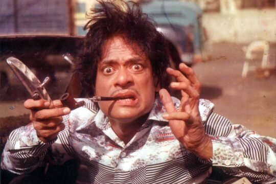 Man with wild hair and exaggerated expression holding two pipes and a mirror.