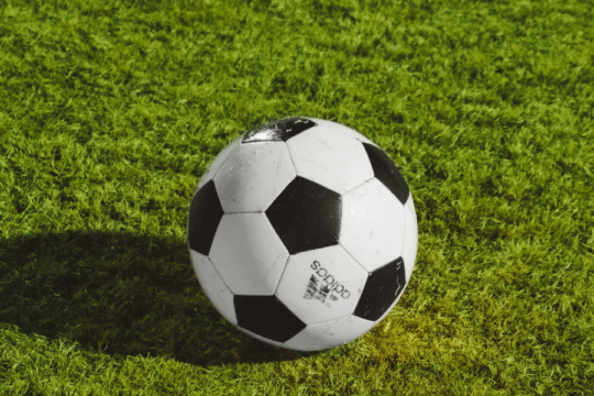 A classic black and white Adidas soccer ball on green grass.