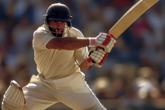 Cricketer in batting stance, helmet, hitting ball.