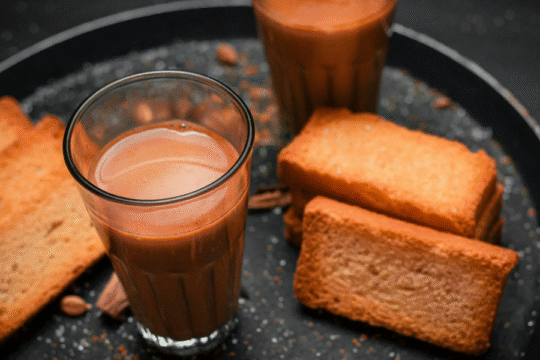 Glasses of chai tea with rusks on a dark tray.