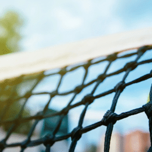A tennis ball stuck in the net on a sunny day.