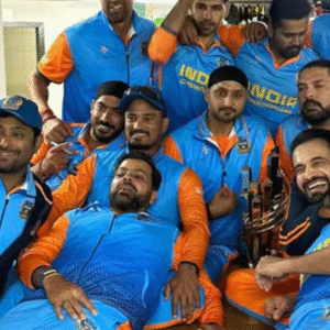 A group of male cricketers in blue and orange uniforms celebrate with a trophy in a locker room.