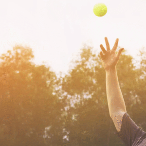 Tennis player serving, ball mid-air, with racket.