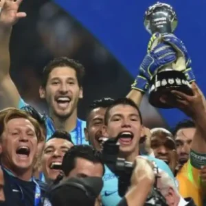 A jubilant soccer team holding up a trophy and celebrating their victory.
