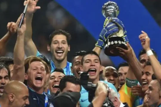 A jubilant soccer team holding up a trophy and celebrating their victory.
