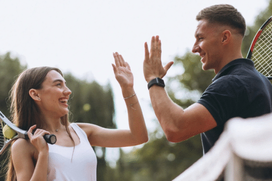 Two happy tennis players giving a high five on the court.
