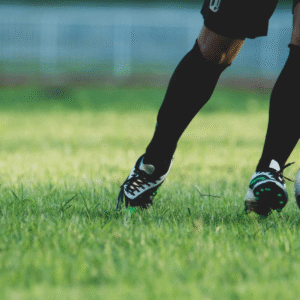 Soccer player's legs dribbling a ball on a green grass field.
