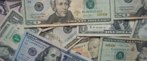 A close-up of various United States dollar bills, including twenty and one hundred dollar notes.