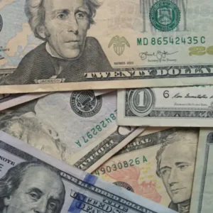 A close-up of various United States dollar bills, including twenty and one hundred dollar notes.